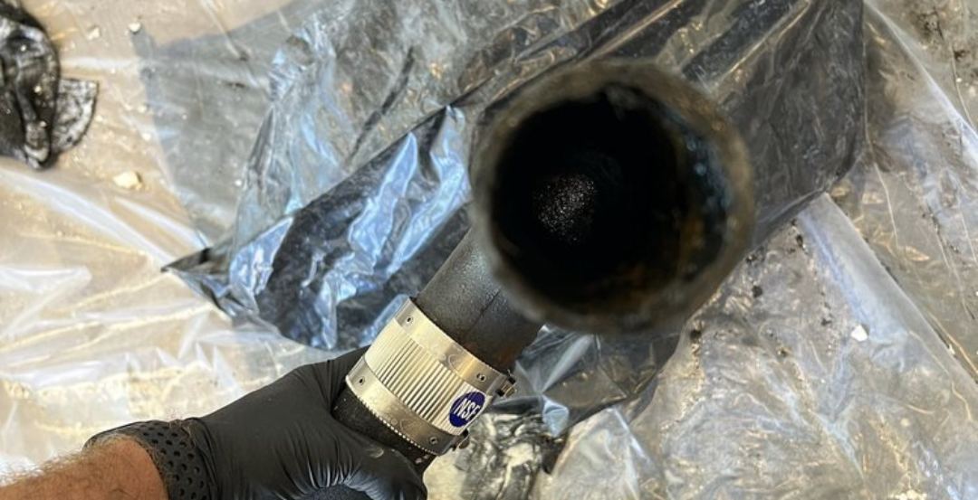 Cross-section of a drain pipe removed by Best Coast Plumbing, showing buildup that had nearly sealed the line