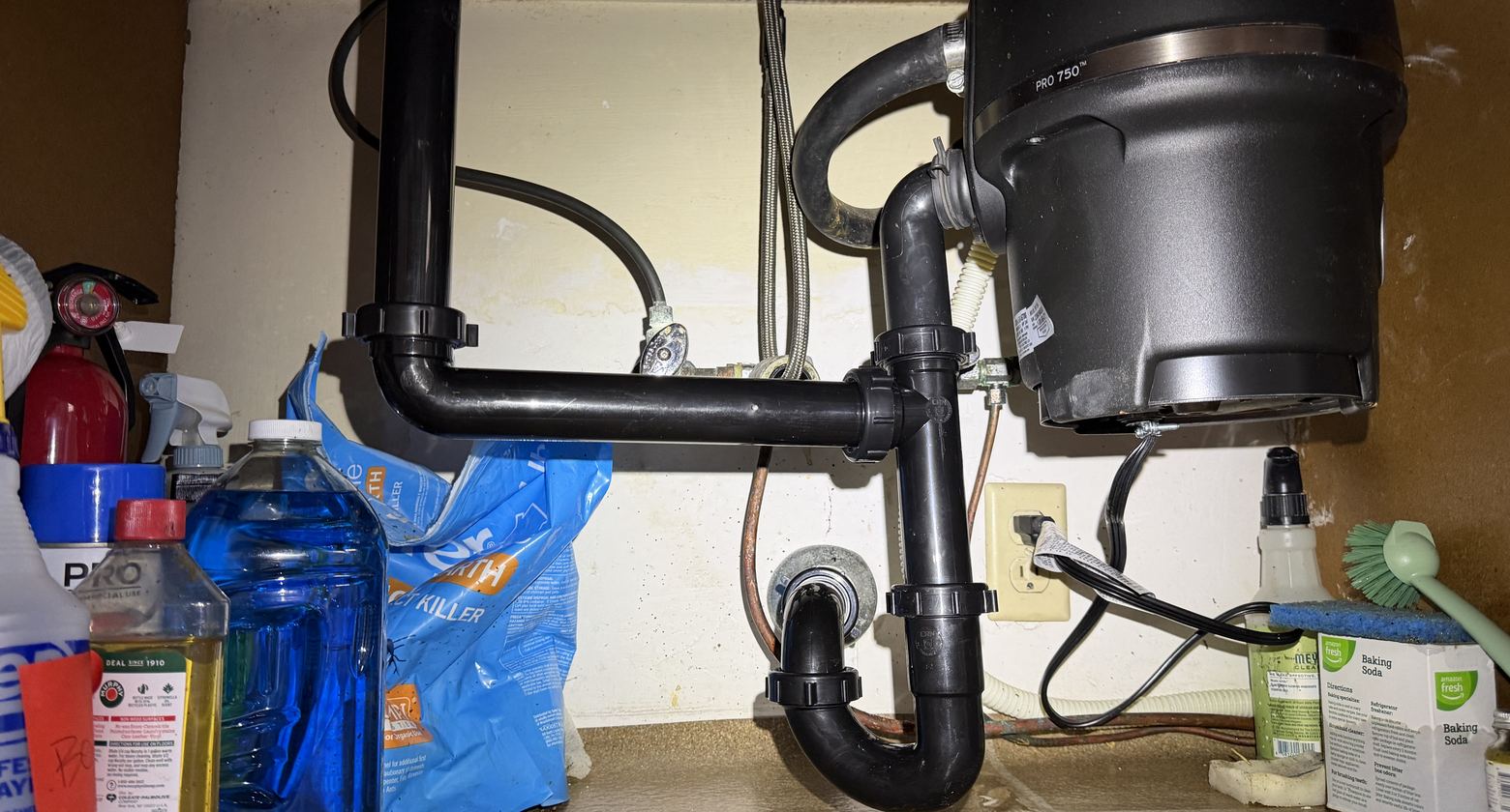 Under-sink drain piping and garbage disposal connections during a Best Coast Plumbing drain service call