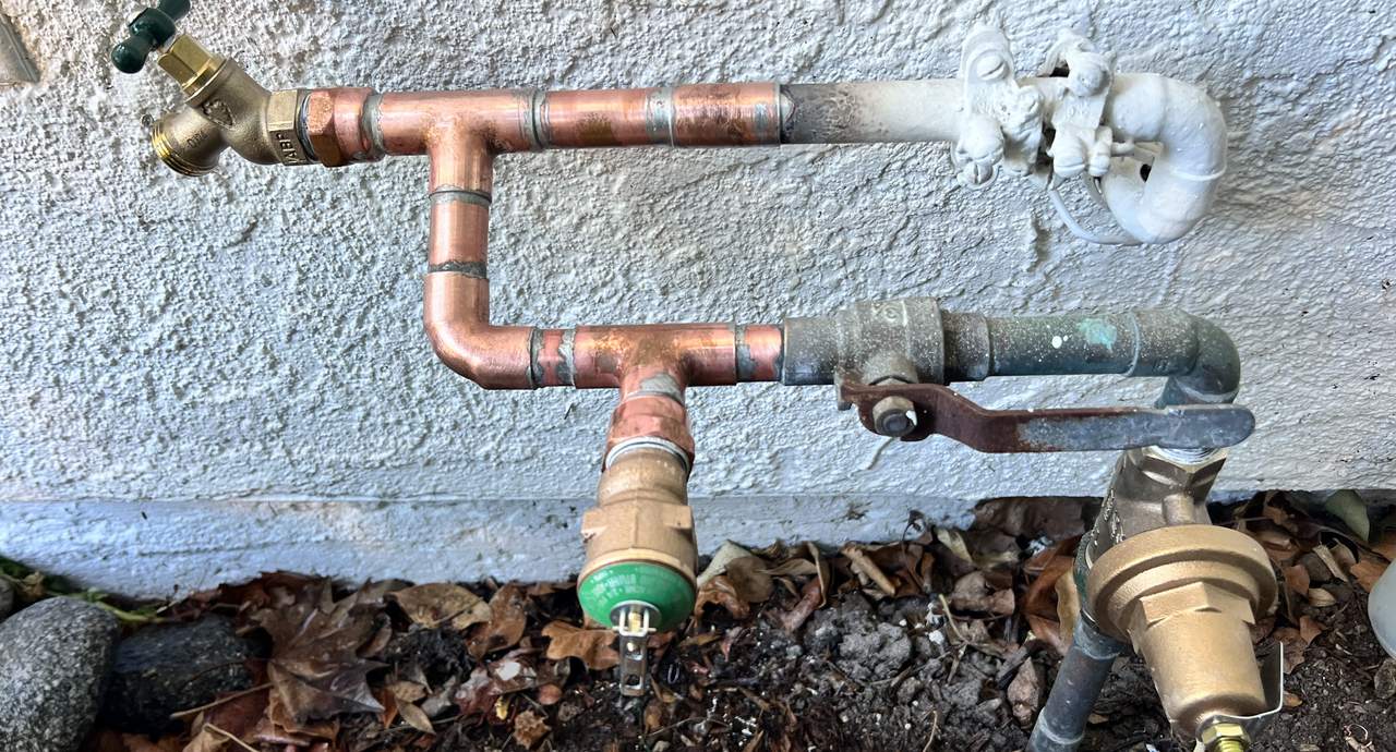 Copper main water supply line and shutoff valves at a home exterior, the first stop in a plumbing emergency