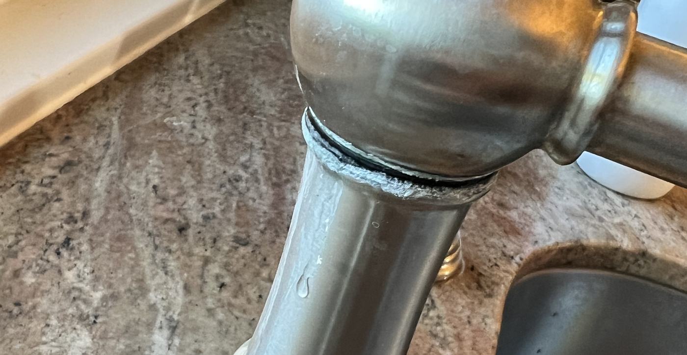 Hard water scale crusted around the joint of a kitchen faucet in a Conejo Valley home