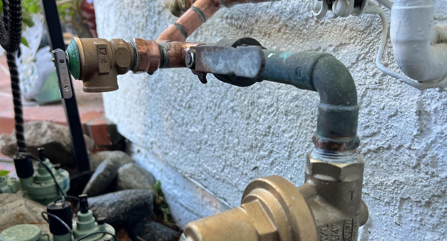 Copper water supply piping and shutoff valves at a home exterior wall, checked during a Best Coast Plumbing inspection