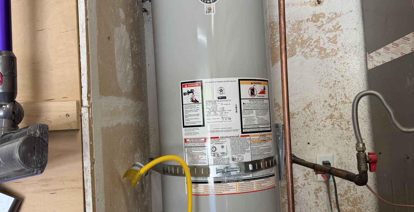 Tank water heater install by Best Coast Plumbing with code-compliant gas flex, drip pan, and connections