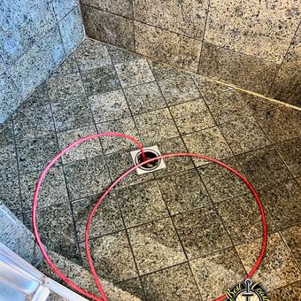 Running a drain snake through a clogged shower drain