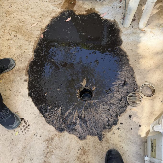 A storm drain basin in Granada Hills full of black silt and standing water before jetting.