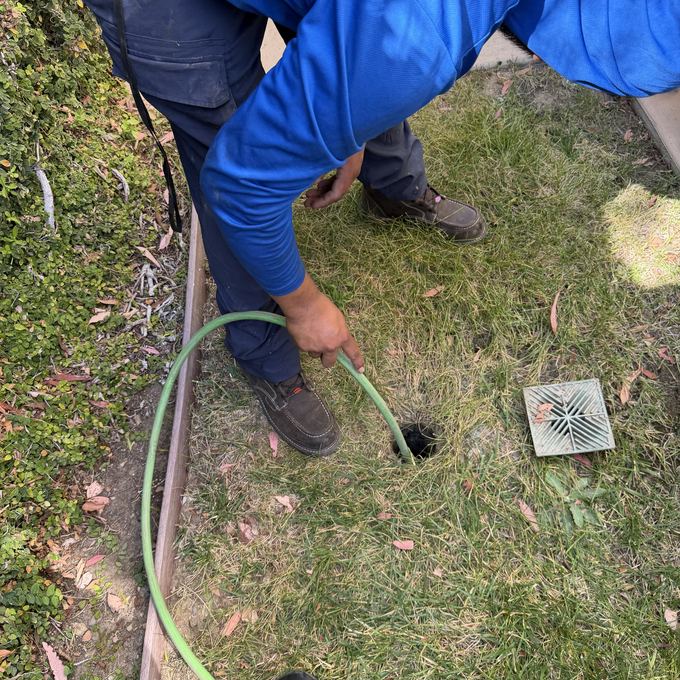 Feeding the hydro jetter hose down a yard drain in Granada Hills after lifting the grate.