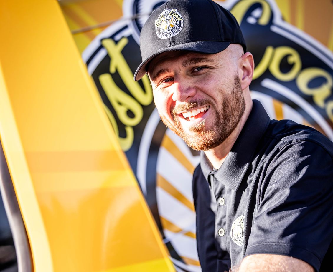 Brendan Lee, founder of Best Coast Plumbing, smiling at the door of his branded service van