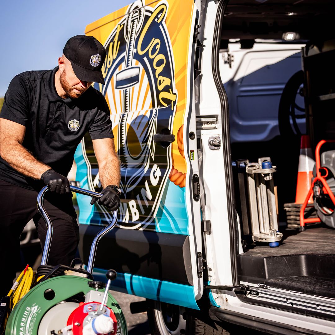 Best Coast Plumbing technician unloading a drain machine from the branded service van