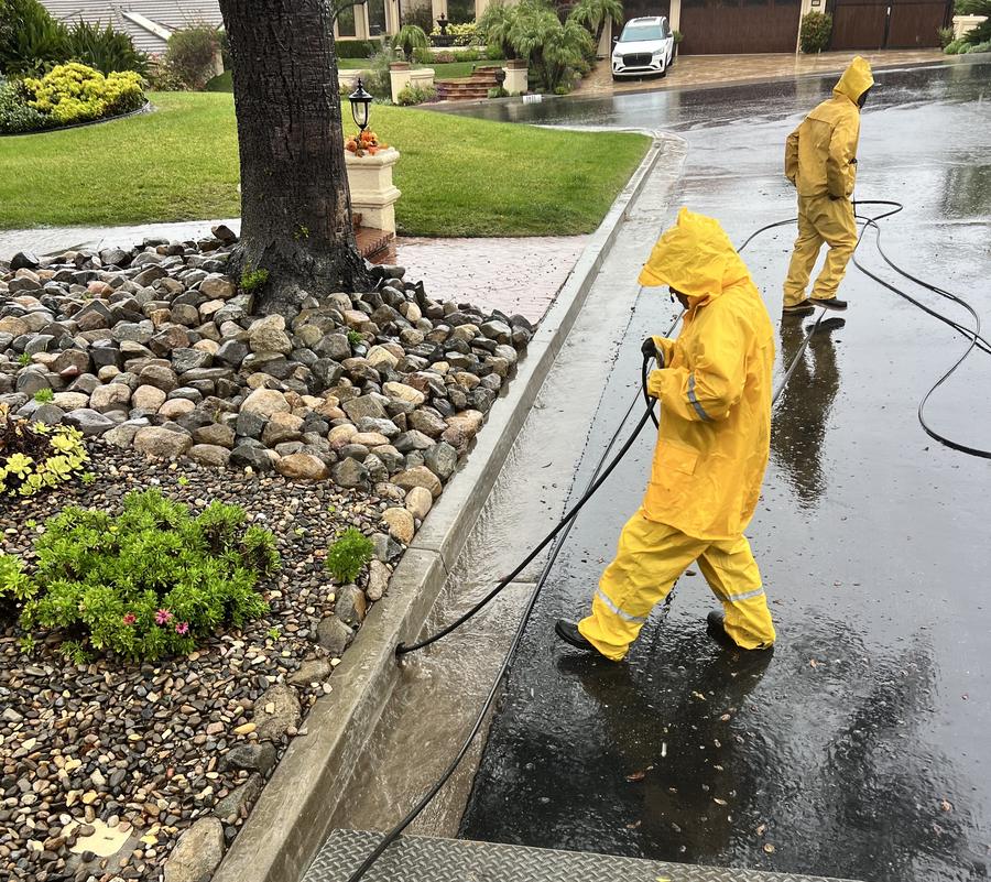 Best Coast Plumbing crew in rain gear running hoses on a flooded street during an emergency call