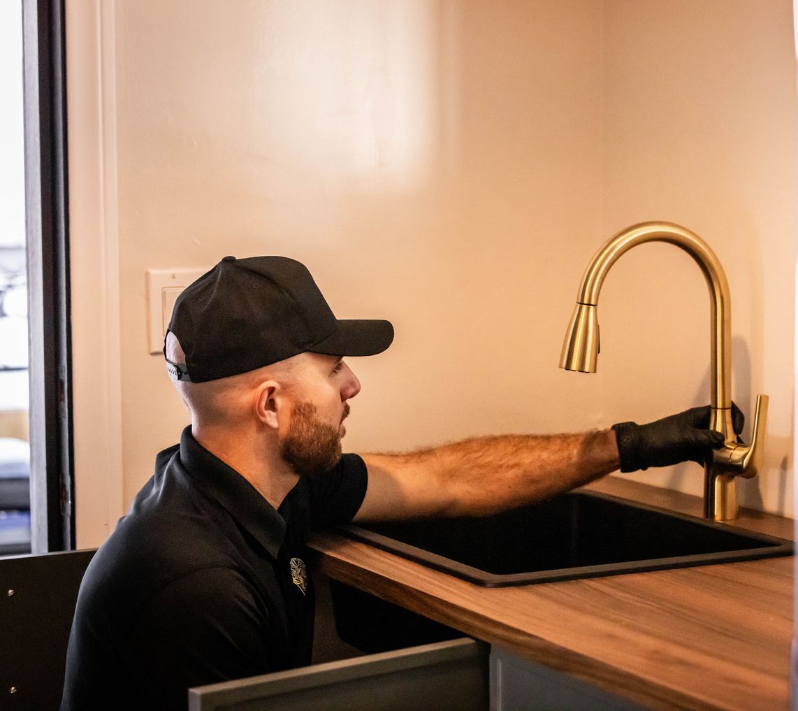 Best Coast Plumbing tech installing a brushed gold pull-down kitchen faucet