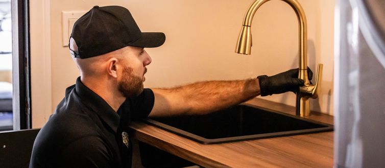 Best Coast Plumbing tech installing a gold pull-down kitchen faucet